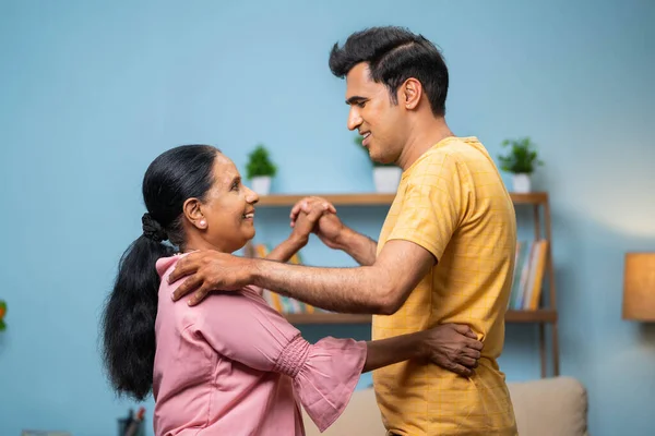 快乐的印度成年儿子 与年迈活跃的母亲一起在家里跳舞 代代相传 娱乐和嬉闹的退休生活方式 — 图库照片