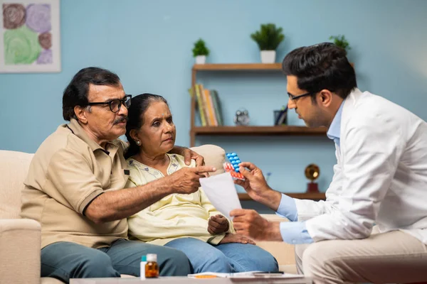 印度医生在家中坐在沙发上解释从处方药到老年病夫妇的药物 家庭保健和咨询的概念 — 图库照片