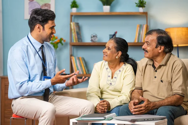 快乐的印度银行家一边坐在沙发上一边向年长的夫妇解释保险政策 财务顾问的概念 银行支持和退休生活方式 — 图库照片