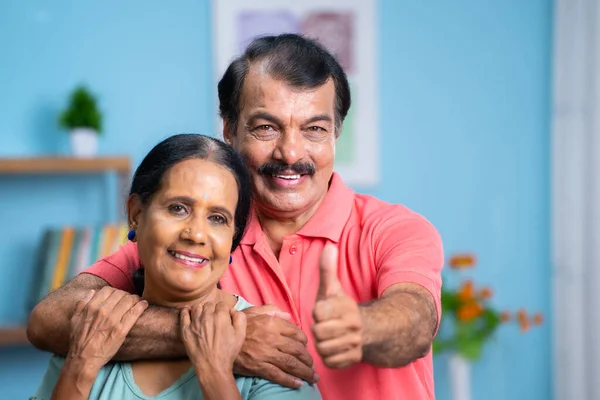 快乐的笑着的印第安老夫妇一边在家里看着相机 一边伸出大拇指 亲密和退休生活方式的概念 — 图库照片