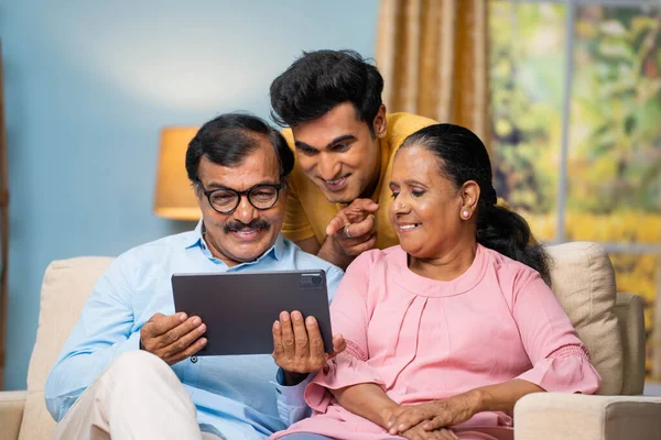 印度老年父母和成年儿子在家里一起聊天 观看数码平板电脑 养育子女和互动的概念 — 图库照片