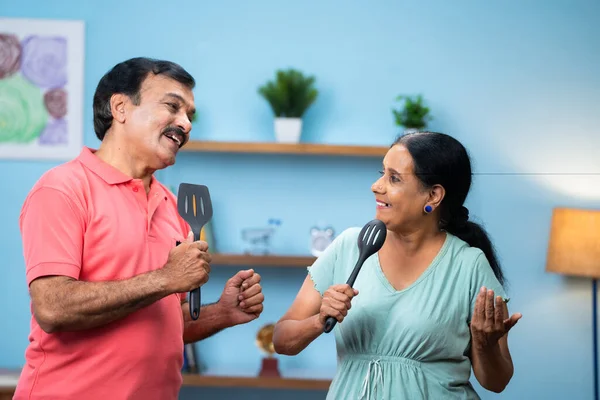 快乐的印度老年夫妇在家里拿着饭碗跳舞唱歌 积极的退休生活方式 热爱感情和健康的关系的概念 — 图库照片