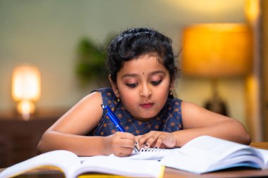 Hintli genç kız evdeki kitap üzerine notlar yazıyor. Eğitim, kendini öğrenme ve zeka kavramı..