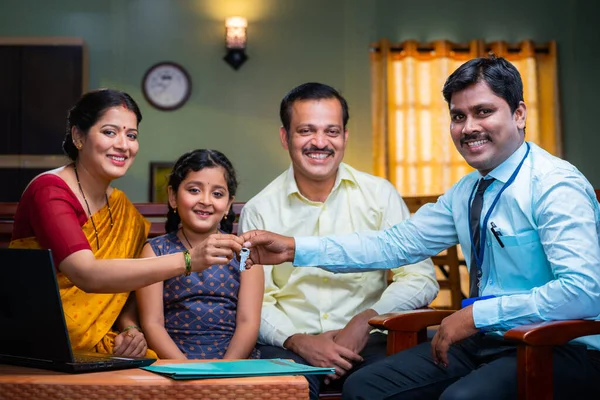 Щасливі Індійські Батьки Дитиною Отримують Ключ Від Банкіра Вдома Дивлячись — стокове фото