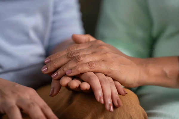 Close up shot of mother consoling to daughter by taking and holding her hands at home - concept of Caring Support, Comforting Gesture and Parental Love or care.