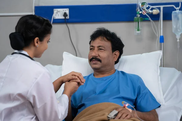 Shoulder shot of indian doctor consoling sick admitted recovered patient by giving confidence at hospital - concept of medical support, Encouragement and reassurance