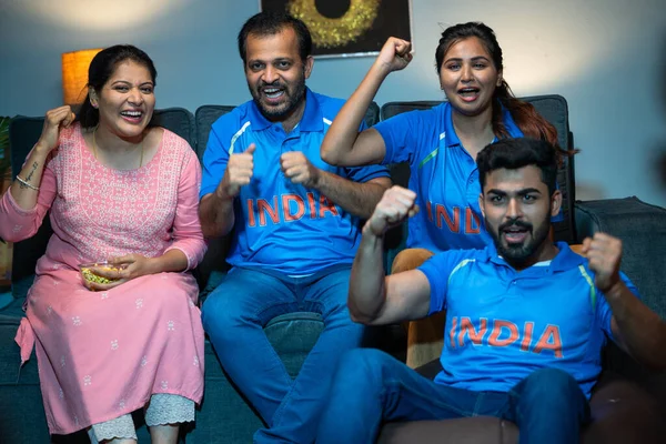 Group of excited encouraging family memebers shouting as India while watching Cricket sports match at home - concept of encouraging, emotional bonding and joyful reaction.
