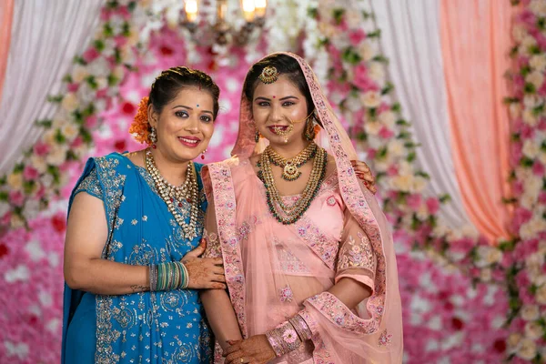 Happy smiling mother with bridal daughter looking or posing to camera on wedding stage - concept of Joyful Moments, Family Love and Wedding Memories