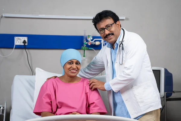 Happy confident indian doctor with recovered cancer patient looking camera at hospital - concept of successful treatment, expertise and medical support.