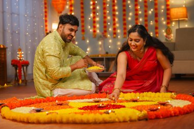 Kocasına odaklan, mutlu Hintli çift evde Rangoli bayramı hazırlıyor. Bayram dekorasyonu, kutlama ve gümrük konsepti.