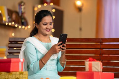 Diwali festivali sırasında cep telefonu kullanan mutlu Hintli kız. Sosyal medya paylaşımı, siber uzay ve bayram dilekleri ya da selamlar gönderme kavramı..