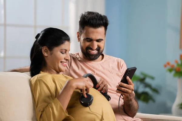 Gelukkige Indiase Man Met Zwangere Vrouw Met Koptelefoon Buik Door — Stockfoto