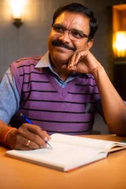 Uyumadan ya da gece yatmadan önce günlük ya da mandıra ya da günlük yazan düşünceli yaşlı adamın dikey çekimi - günlük, liste ve günlük rutin yazma kavramı.