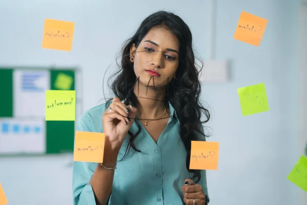 young Indian woman planning at office for project completion or business strategy by writing - concept of workplace analysis, startup culture and creative innovation.