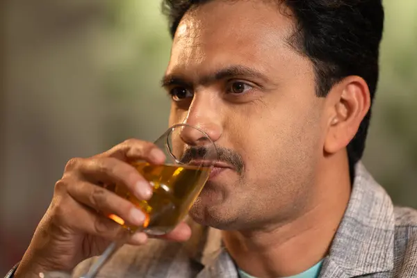 Close up shot of middle aged Indian man drinking wine at weekend night party at restaurant - concept of luxury lifestyles, refreshment and relaxation.