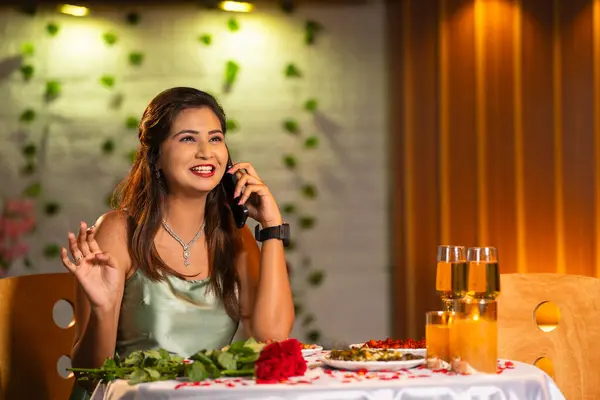 happy excited woman speaking on mobile phone call during candlelight dinner at restaurant while waiting - concept of valentines day, date night plan and glamours