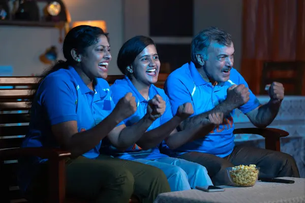 Cheerful family shouting as India india while watching live cricket match on tv or television for encouragement at home - concept Entertainment, family bonding and celebration