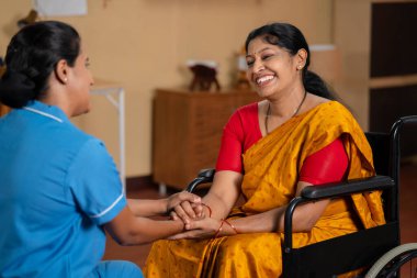 Mutlu Hintli hemşire ya da bakıcı tekerlekli sandalyedeki iyileşmiş kadın ya da hasta ile konuşuyor - mesleki meslek anlayışı, şefkat ve teşvik kavramı.