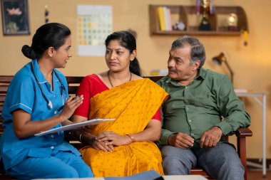 Evde sağlık kontrolü sırasında yaşlı çiftlere güven veren Hintli hemşire - sağlık terapisi oturumu, sağlık hizmeti ve tıbbi danışmanlık.