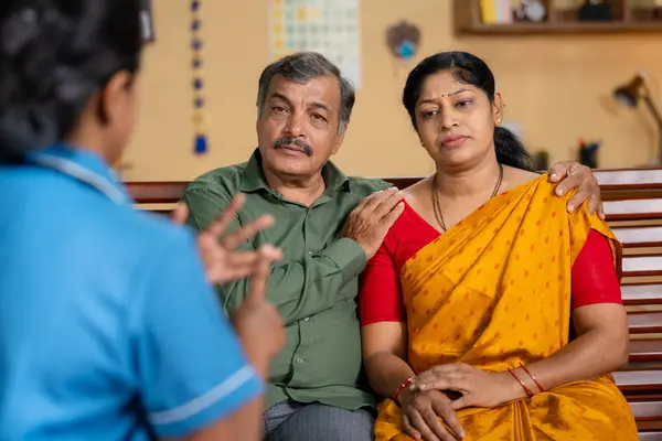 Shoulder shot of Nurse or caretaker giving advice to Senior woman while sitting with caring wife at home - concept of consultation, mental wellness and healthcare service.