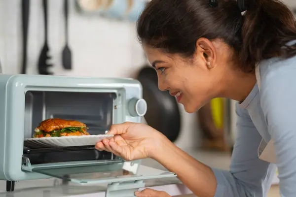 Щаслива Індійська Жінка Готує Бургер Розмістивши Його Мікрохвильовій Печі Кухні Стокове Фото