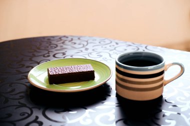 Masanın üzerinde bir fincan kahve ve waffle tabağı var. Yakın plan.