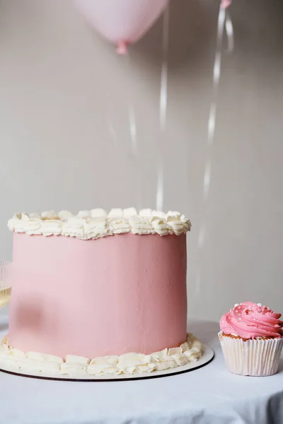 A large beautiful pink cake with the inscription Birthday on a white table close-up. Birthday cake