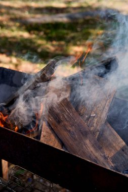 Izgarada ateş yanıyor. Izgara yakın çekim. Yakından bakınca odun yakıyor.