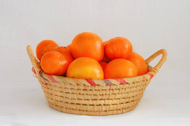 Beyaz arka planda portakal ve mandalinalı hasır sepet