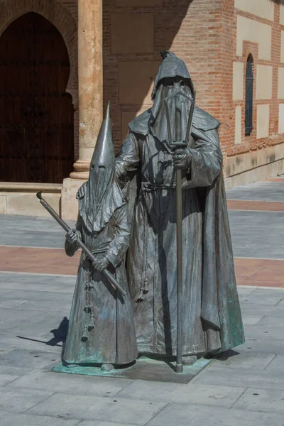 stock image Two bronze sculptures representing two holy week penitents in a square in Guadalajara. Spain