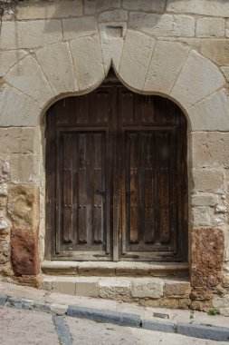 Eski bir binanın ön cephesinde ogee kemeri olan eski ahşap kapı.