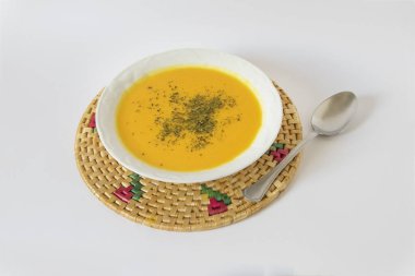 Beyaz arka planda kabak kremalı ve kaşıklı tabak