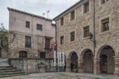 Guadalajara 'nın Sigenza eyaletindeki Plaza de la Carcel' in bir köşesinde yarı dairesel kemer ve merdivenlere sahip taş binalar. İspanya