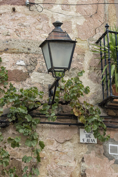 Old street lamp in stone wall with green leaves