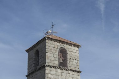 Çanları ve çatısı leylek olan bir kilise kulesinin tepesinde.