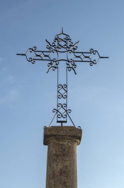 Arka planda gökyüzüne karşı işlenmiş bir demir haç silueti.