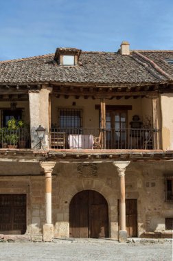 Verandasında sütunları olan taş bir ev ve Segovia 'nın Pedraza ilinde yarı dairesel kemerli ahşap bir kapı. İspanya