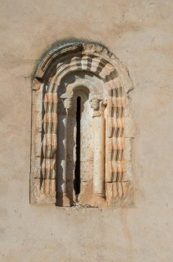 Romanesque window with columns and semicircular arch in the wall of a church clipart