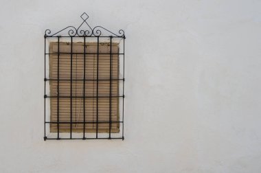 İspanya 'da beyaz duvarda kepenk ve tipik La Mancha ızgarası olan kapalı pencere