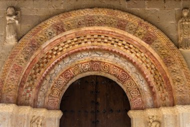 Romanesque archivolts of a church with relief and red painted  clipart