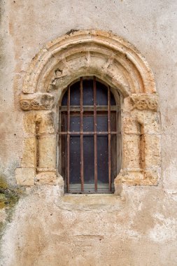 small window with semicircular stone arch and iron grille in Romanesque style clipart