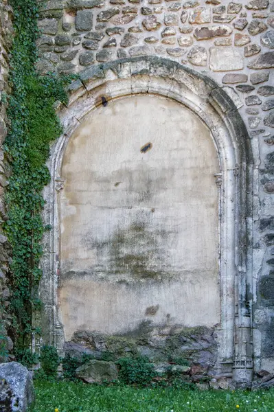 stock image a stone wall with a blind gothic arch surrounded by ivy