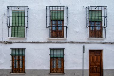 Tipik mançalı parmaklıklı uzun pencereler ve Toledo ilinin Ocaa şehrinde beyaz bir evin ön cephesinde ahşap kapılar. İspanya