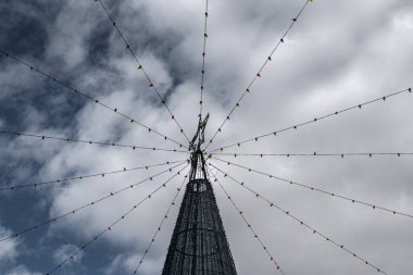 Yıldızlı ve renkli ampullü bir Noel ağacının tepesinde, bulutlu bir gökyüzünde izole edilmiş.