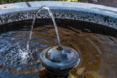 Ortasında bir su püskürtüsü olan küçük dairesel çeşme.