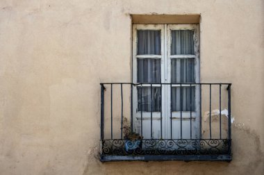 Eski bir balkon, ahşap, cam kapı ve metal korkuluklar eski bir cephede