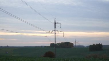 A high power line landscape in the countryside in the evening. The electric poles in a panoramic scene on a plain. The beautiful rural location with industrial infrastructure.