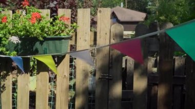 Çiçek kutusu ve bayrak ile süslenmiş özel bir ev çiti. Bahçe partisinde şenlikli bir ortam yaratmak için güzel bir örnek. Yazın neşeli bir tatil sahnesi.