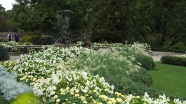 Riga, Letonya - 25 Ağustos 2023. Letonya başkentinin parkında yeşillik tasarımı. Gençler, güzel yaz çiçeklerinin yanındaki çeşmede oturup Opera Meydanı 'nda dinleniyorlar..