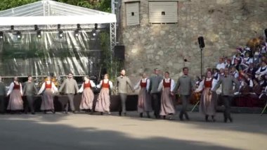 Dobele, Letonya - 27 Mayıs 2023. Sahnedeki dansçılar, Letonya halkının zengin dans kültürünü otantik performanslarla kutlayarak geleneksel Letonya halk danslarını (sesle) sergiliyorlar..